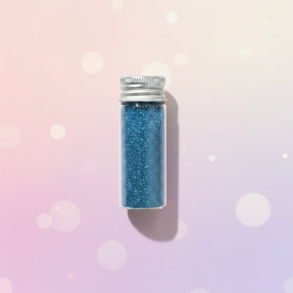 Escarcha comestible glitter color azul en frasco de vidrio 10 gr sobre fondo bokeh rosa pastel – glitter para tortas y repostería - Vallia Reposteria