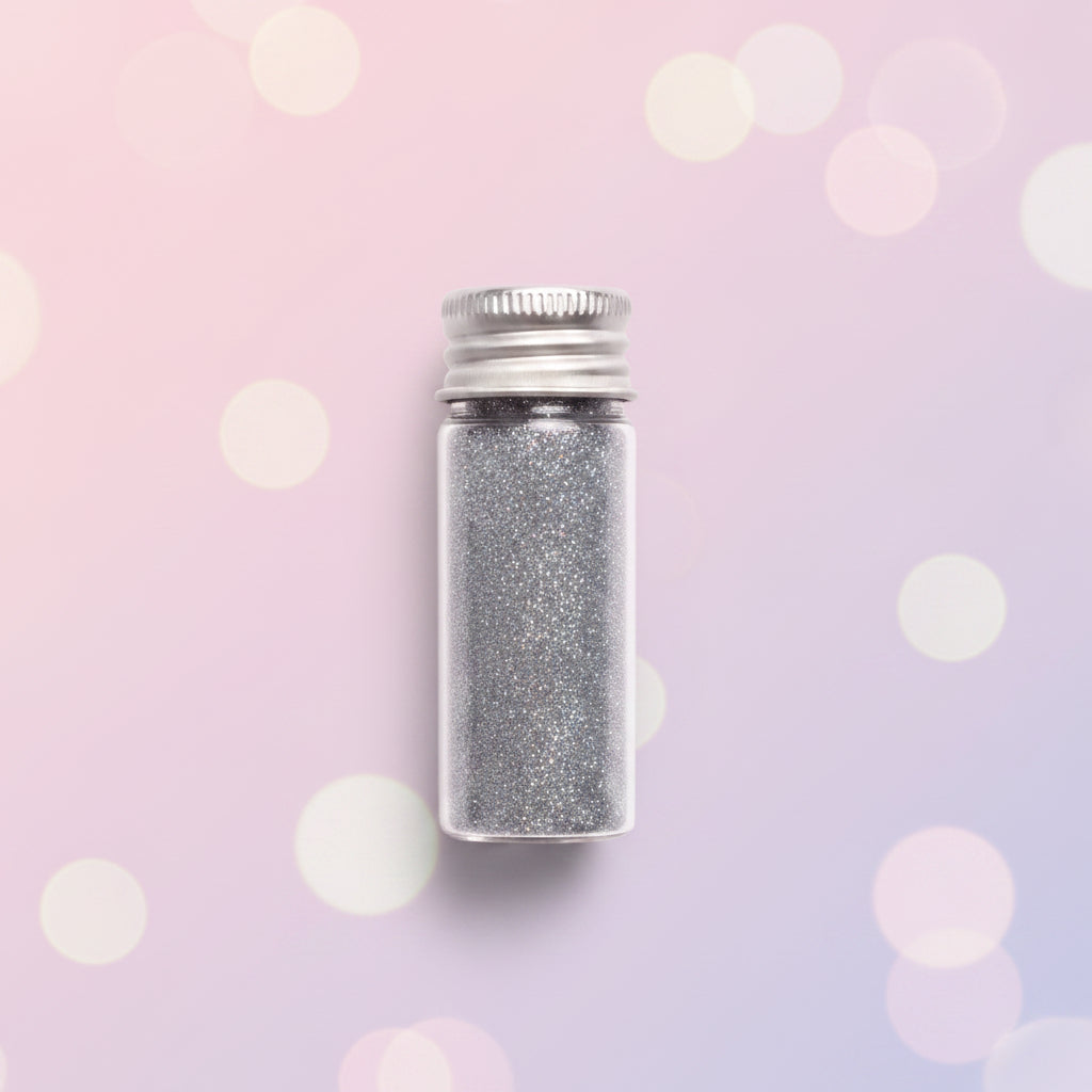 Escarcha comestible glitter plateado en frasco de vidrio con tapa metálica 10 gr sobre fondo bokeh rosa – glitter para repostería - Vallia Reposteria