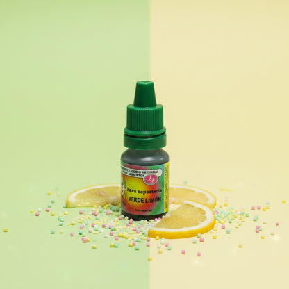 Colorante líquido hidrosoluble Colorisa verde limón con frasco gotero sobre fondo bicolor y rodajas de limón – colorante para repostería - Vallia Reposteria