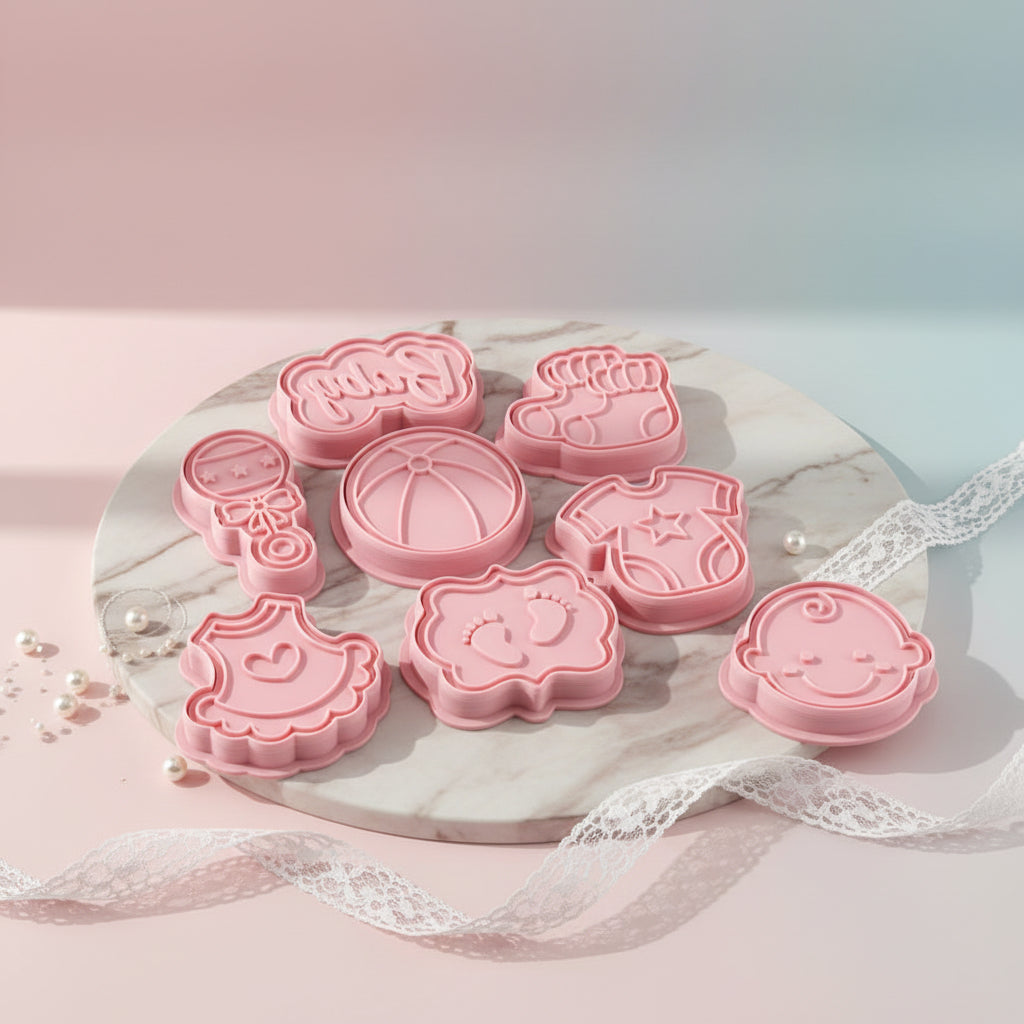 "Kit de 8 sellos y cortadores rosados para repostería temática de bebé: sonajero, huellas de pies, carita de bebé y texto Baby para decoración de galletas."