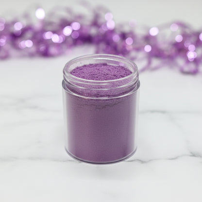 Polvo matizador comestible Morado Elegante en frasco transparente con fondo bokeh lila – colorante para repostería fina - Vallia Reposteria