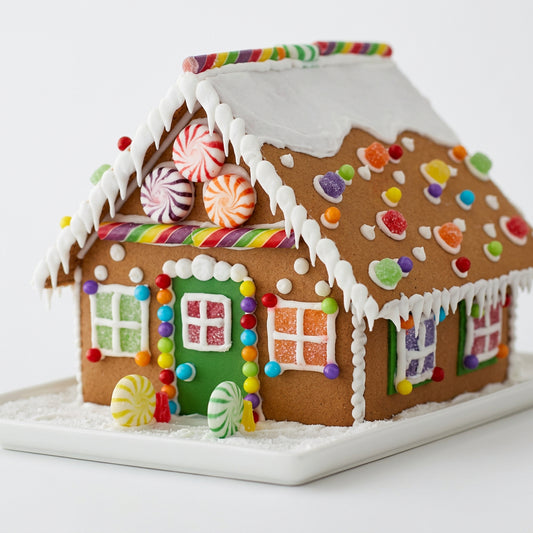 Casita de jengibre artesanal de Vallia Repostería decorada con glaseado blanco, caramelos coloridos y dulces festivos