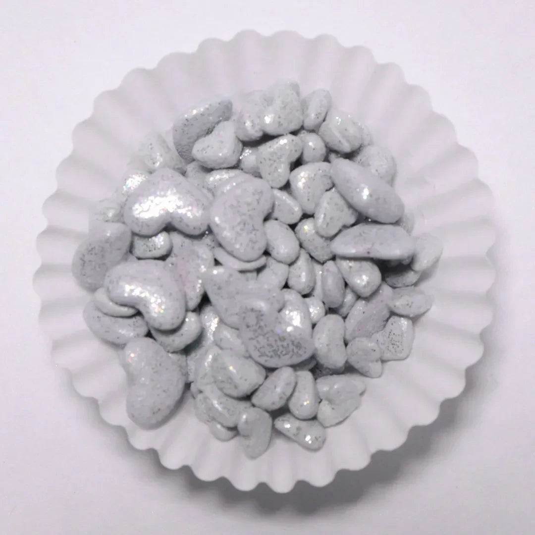 Grageas de corazón blancas con acabado brillante comestible de Vallia Repostería en un capacillo de papel