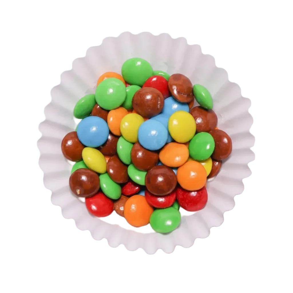 Mini lentejas de chocolate confitado de colores surtidos en un capacillo blanco de Vallia Repostería