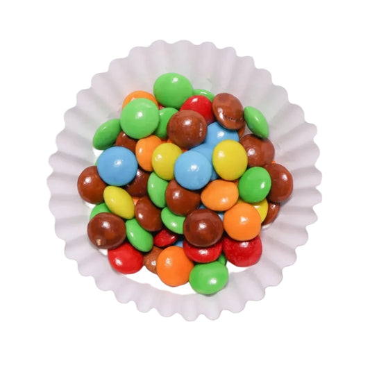 Mini lentejas de chocolate confitado de colores surtidos en un capacillo blanco de Vallia Repostería