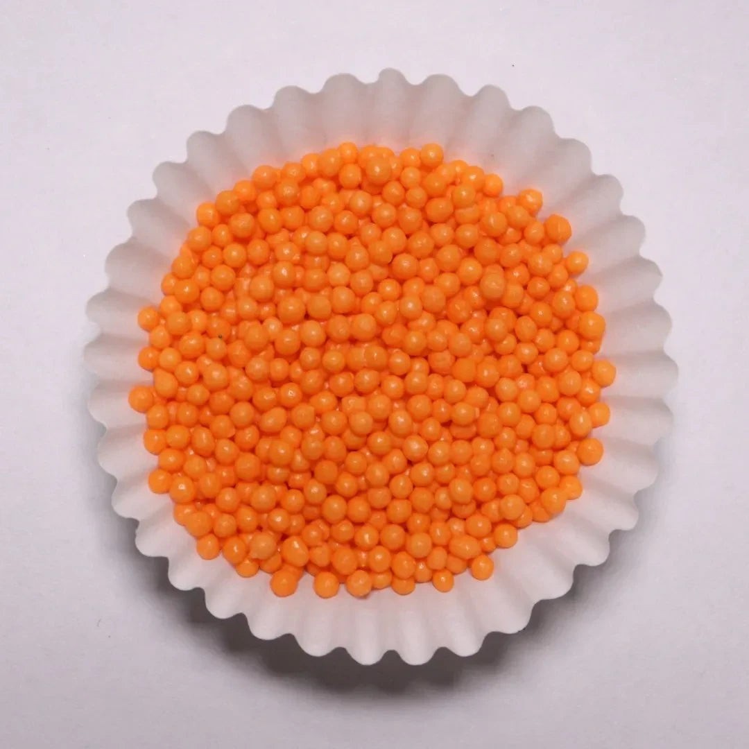 Grageas redondas mini de color naranja brillante en un capacillo blanco, ideales para decorar postres Vallia Repostería