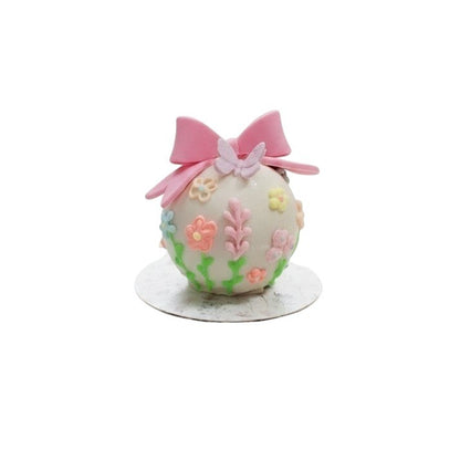 Esfera de chocolate decorada con mariposas y flores de fondant de Vallia Repostería sobre una base de encaje blanco.
